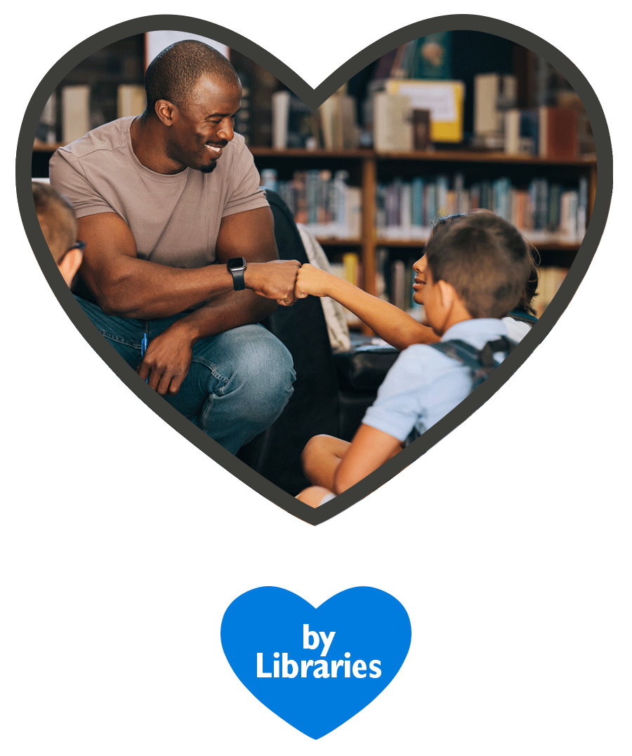 Empowered by Libraries - A man fist-bumps with one of a group of students sitting on the floor of a library.